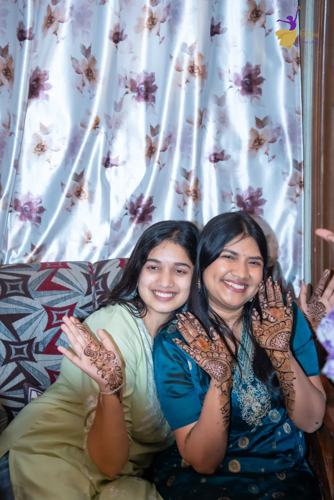 Priyanka and a friend laughing and clapping their henna hands together