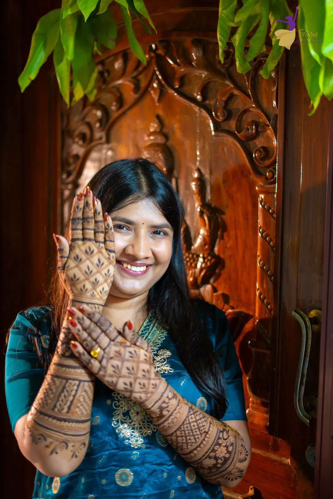 Bridal portrait of Priyanka showing her mehendi by a carved doorway