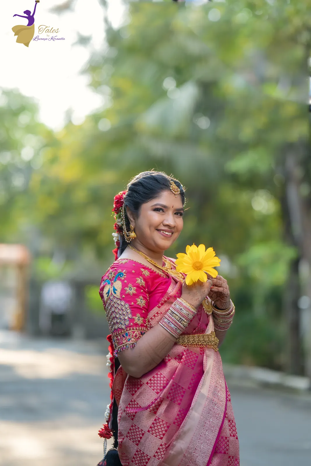 Priyanka holding a yellow flower on a tree-lined road at sunrise