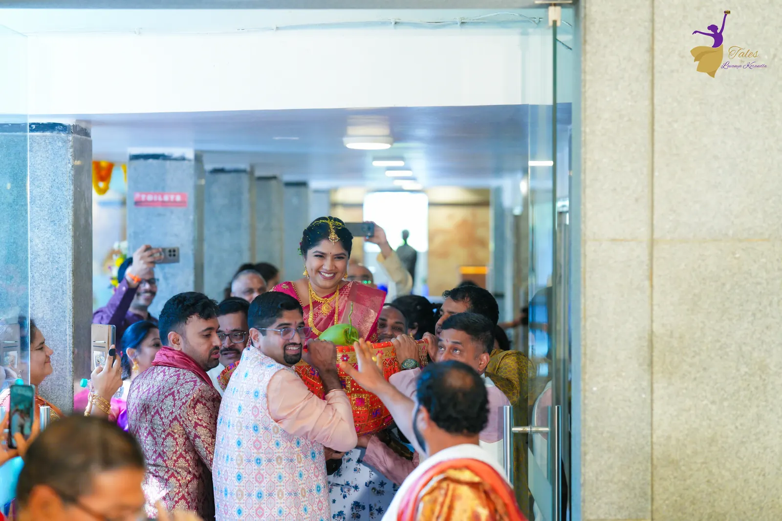 Wide shot of family crowding the corridor as Priyanka is carried in for the wedding