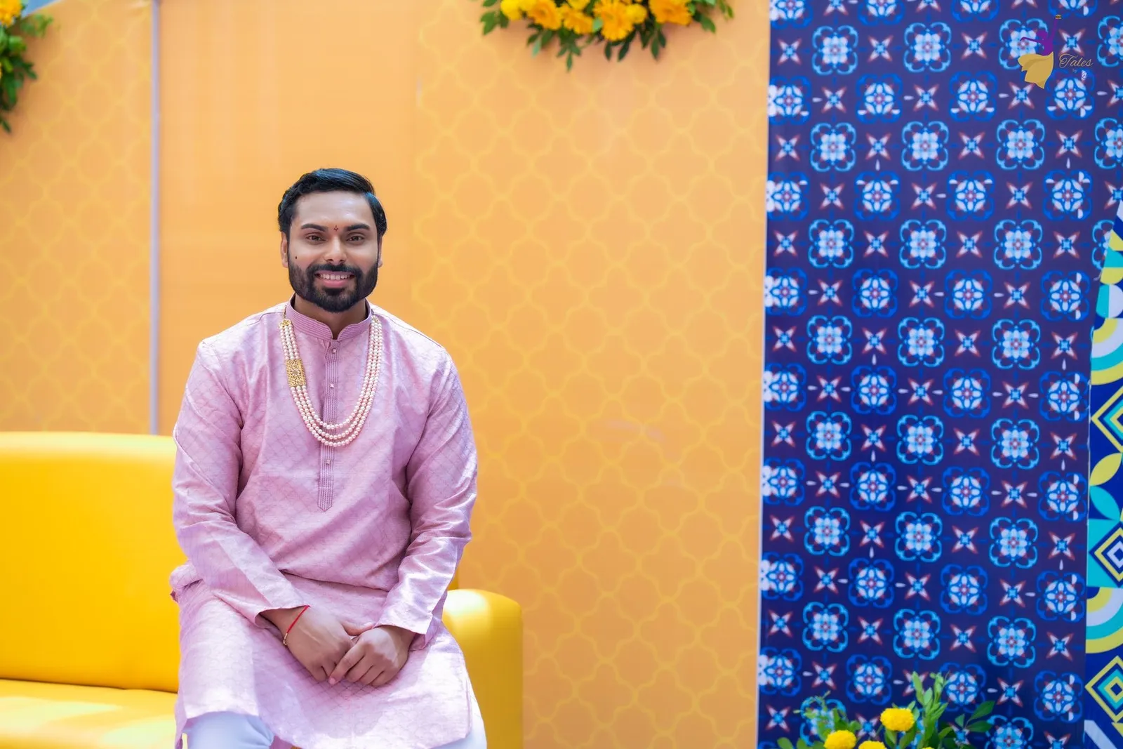 Manoj in light pink kurta seated on yellow sofa at Haldi