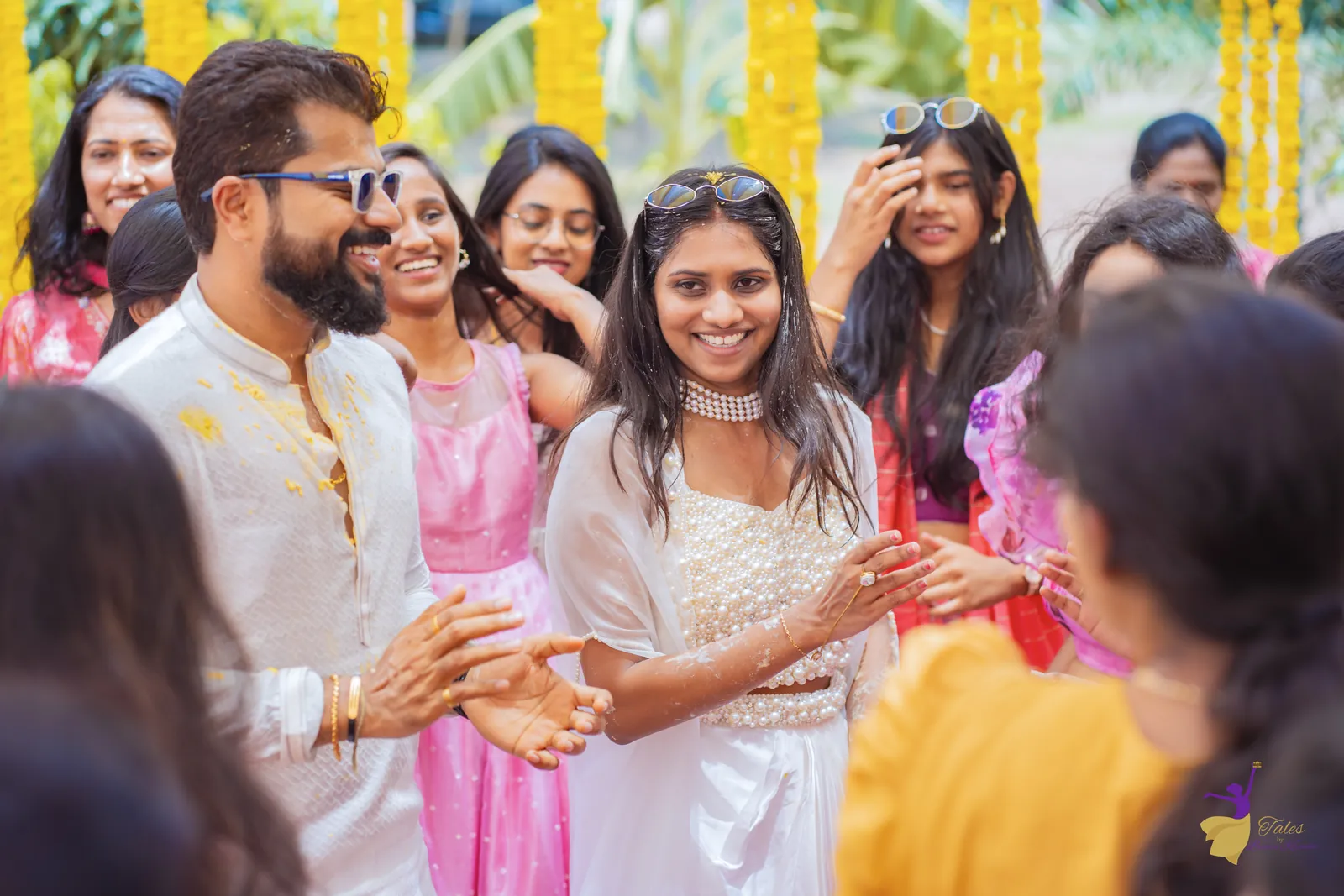 The bride laughing and clapping with cousins and the groom at the haldi