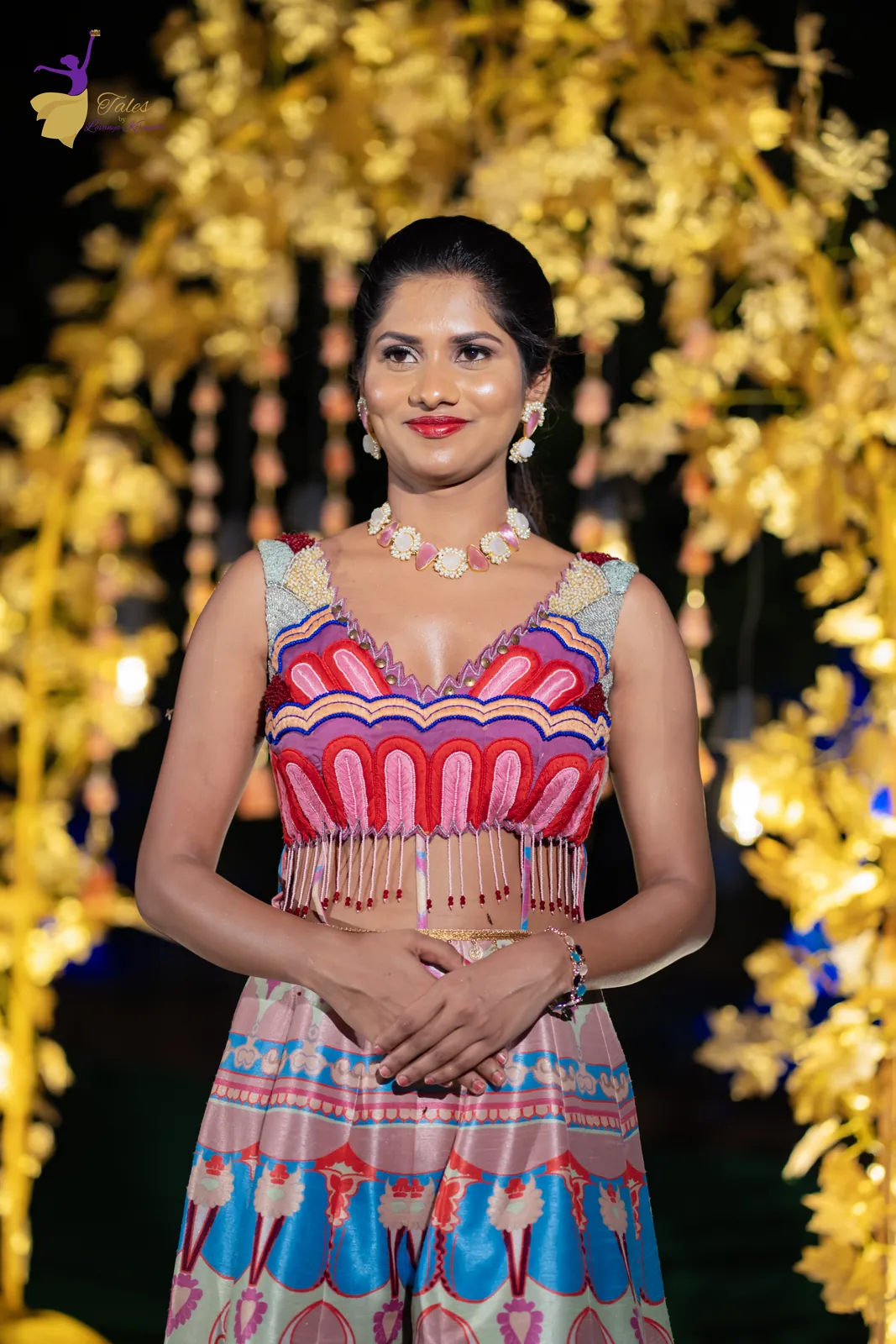 Vishwasa in a colourful printed lehenga smiling before golden floral decor at night
