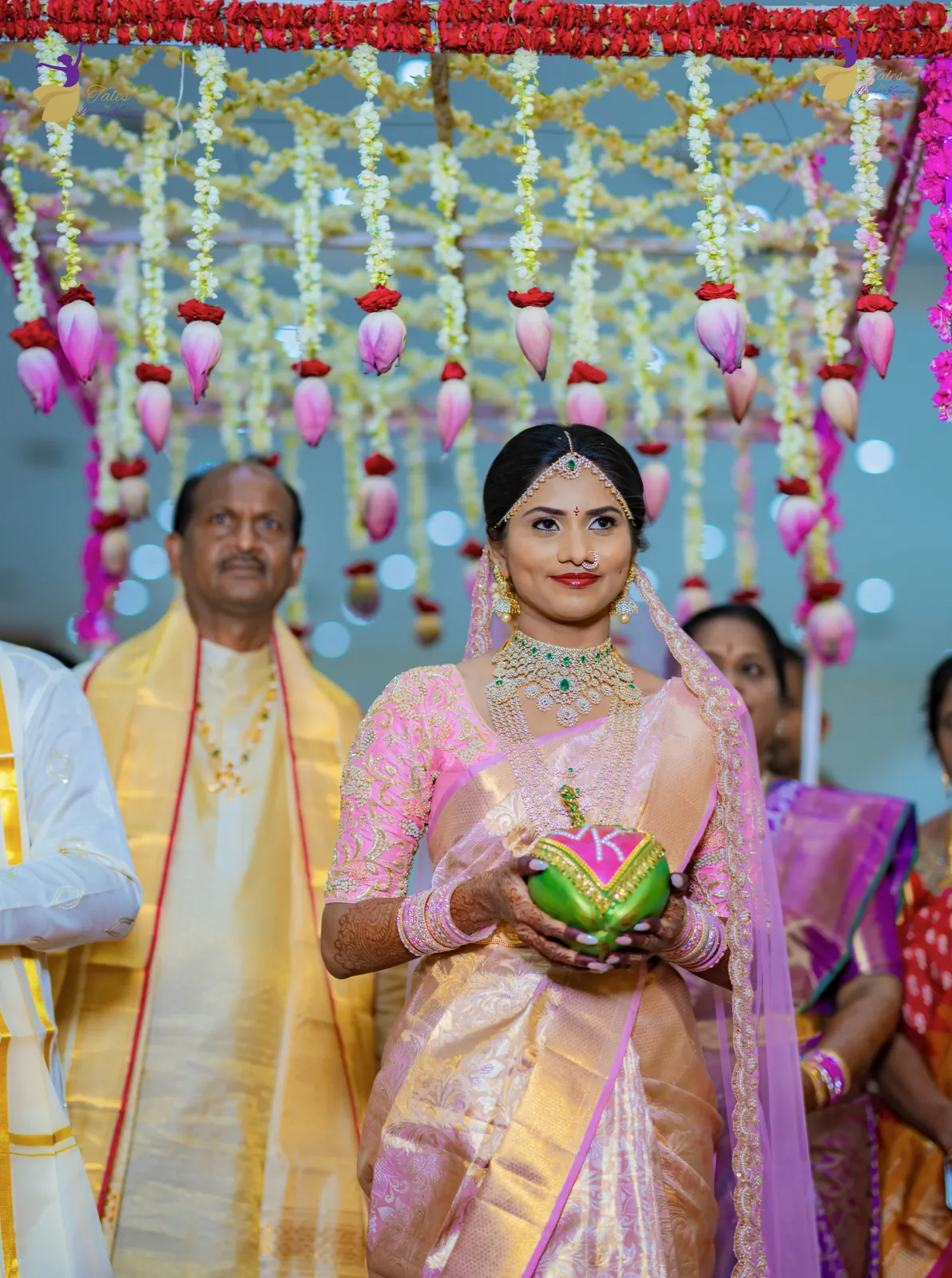 The bride’s entry under a floral canopy, holding a decorated coconut, surrounded by family