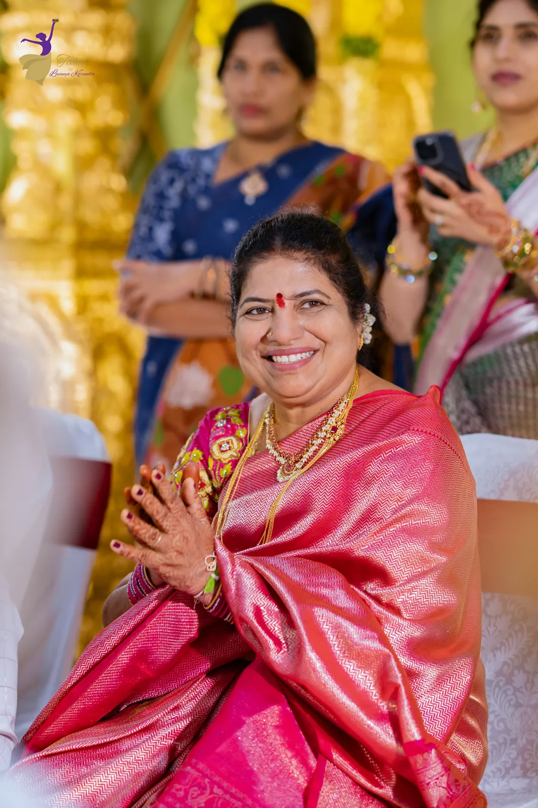 A family member in pink silk laughing with joy during the wedding rituals