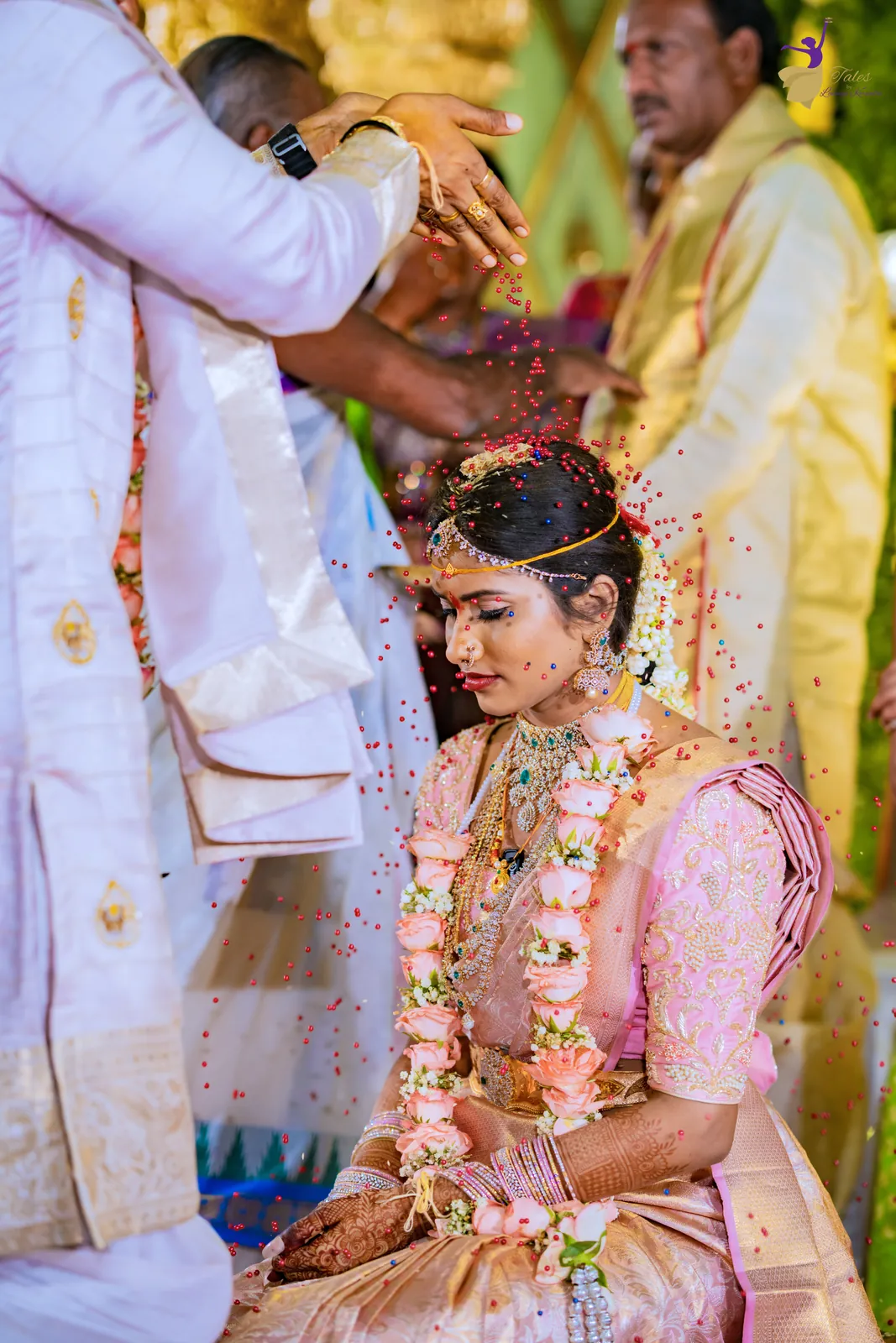 Talambralu: the groom showering rice over the garlanded bride on the mandap