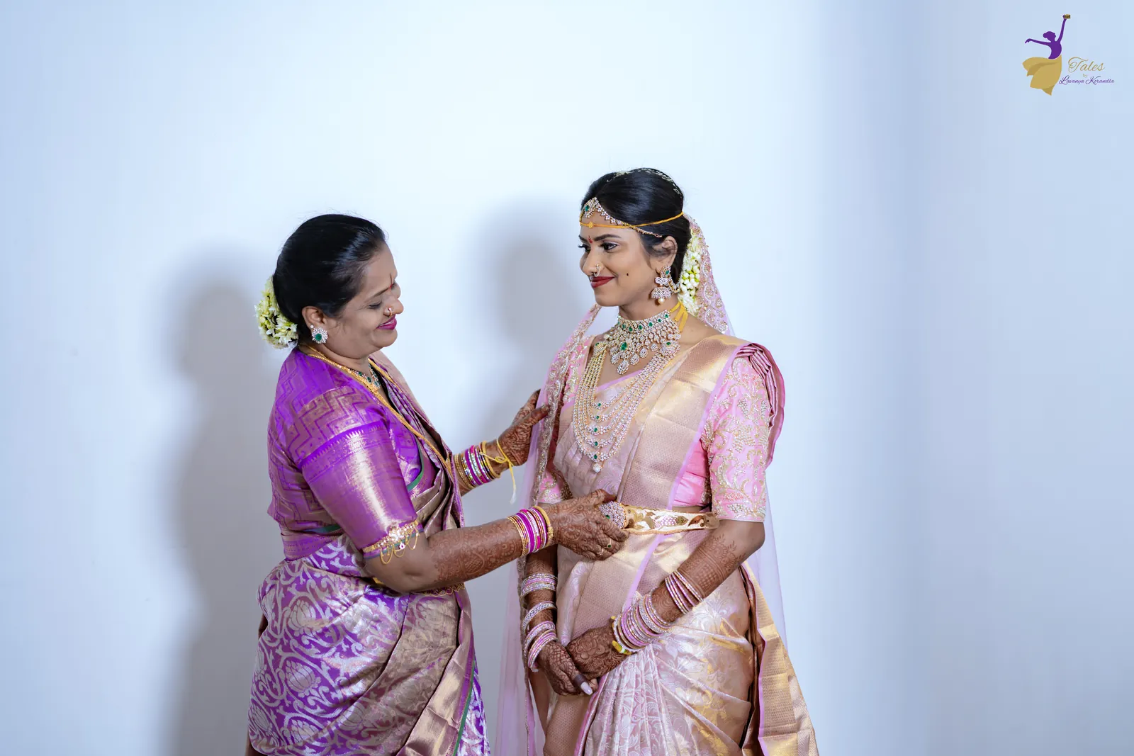 The bride’s mother adjusting her pink silk saree as she gets ready