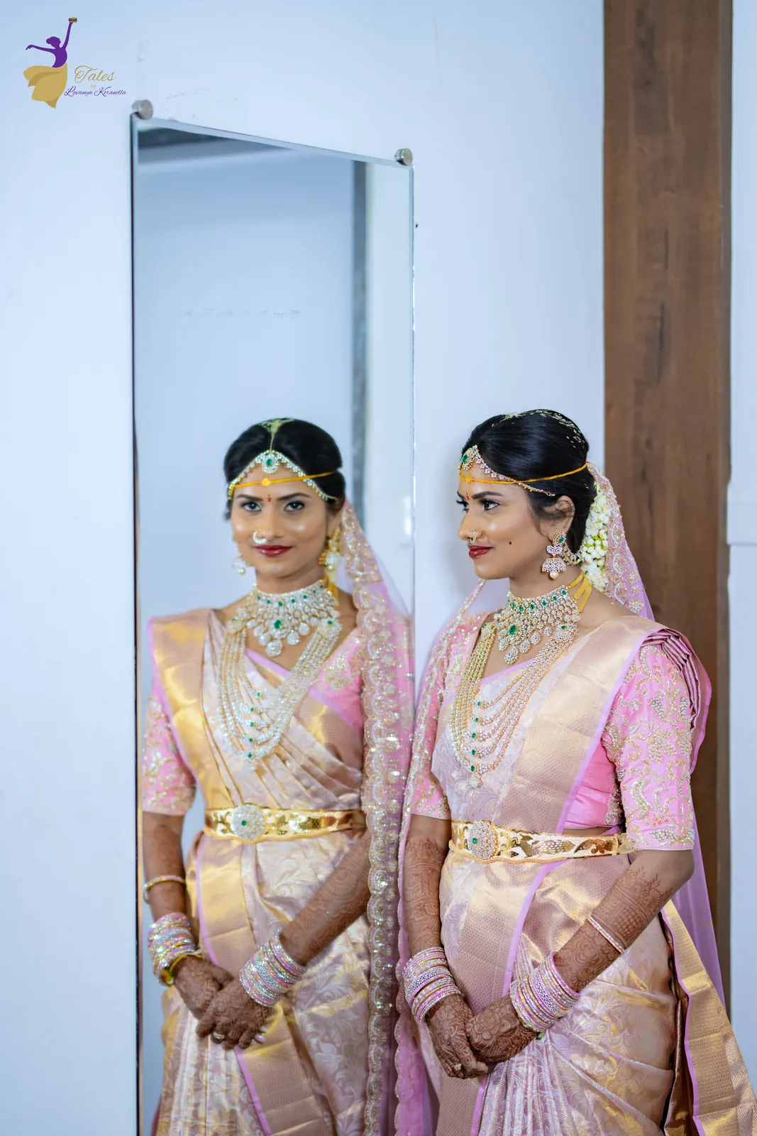 The bride in pink silk beside a mirror reflecting her bridal look