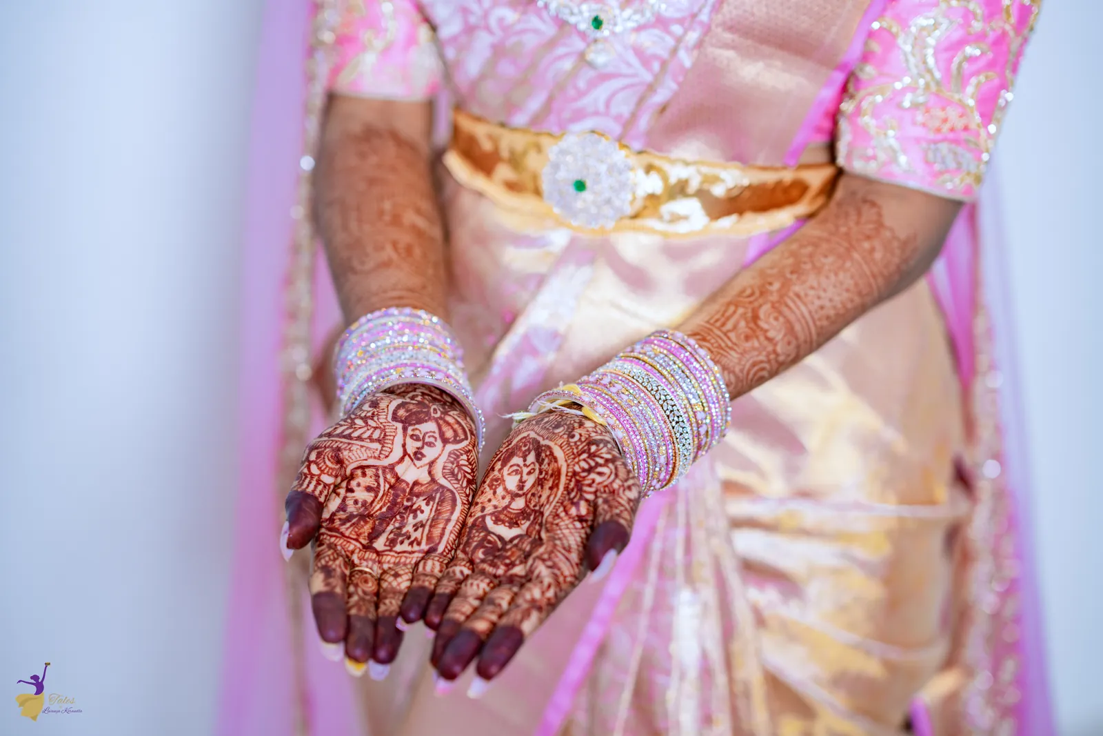 Close-up of the bride’s mehendi hands and gold bangles against her pink silk saree