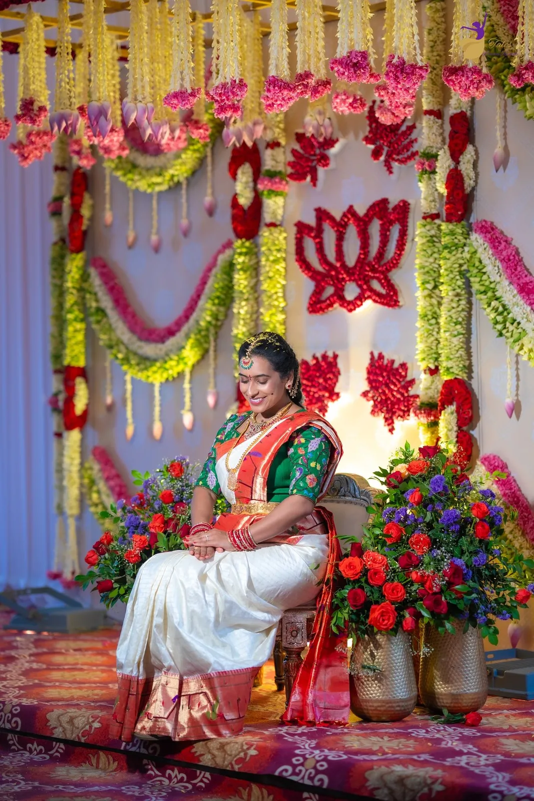 Priya seated on a marigold and lotus-decked stage with brass pots at her Pellikuthuru ceremony, Amalapuram – TBLK
