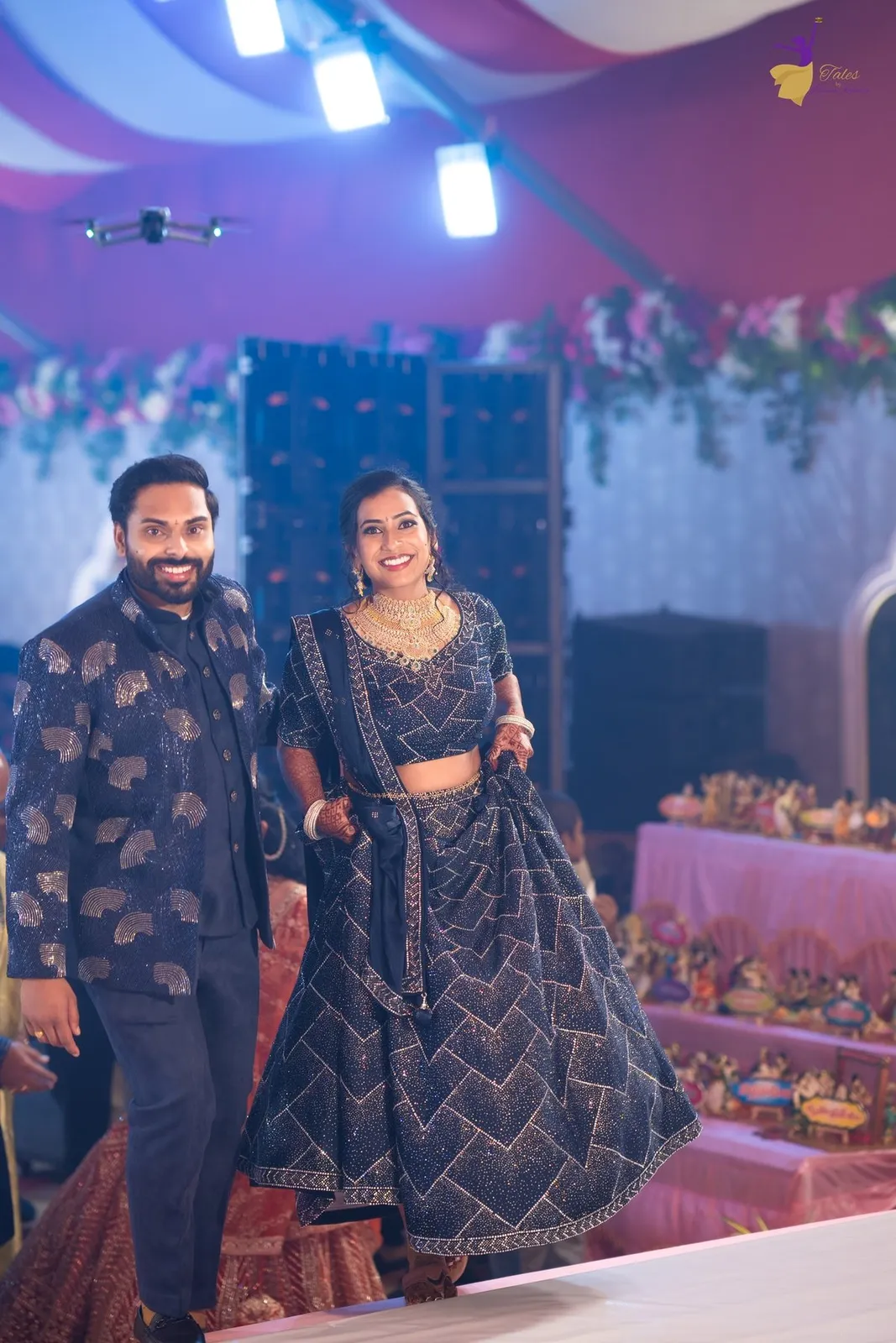 Couple portrait in navy blue before marigold and rose backdrop