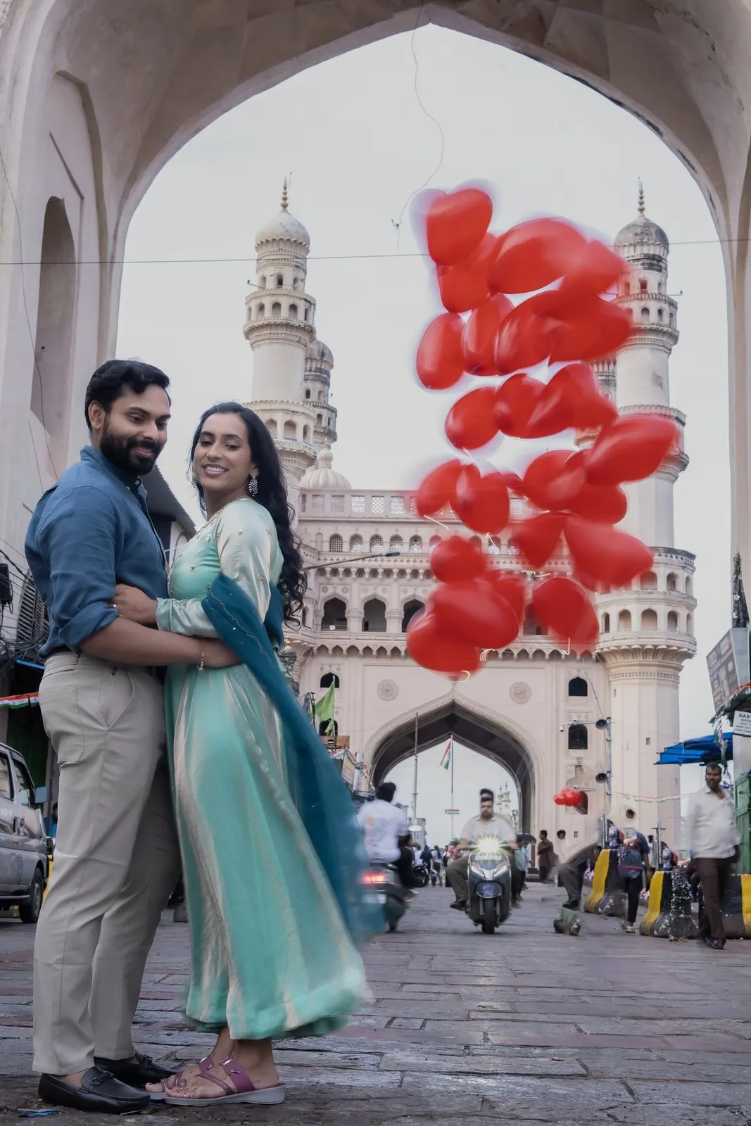 Manoj and Priya with red heart balloons under Charminar arches