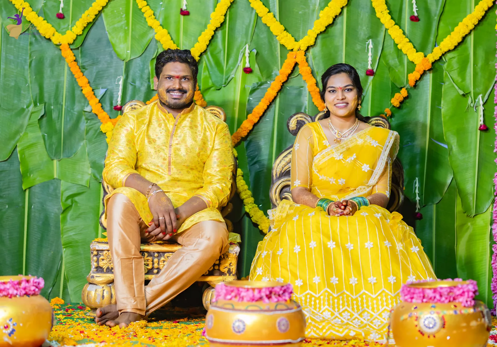 Ravinder and Anuhya in yellow seated side by side before a banana-leaf and marigold haldi backdrop
