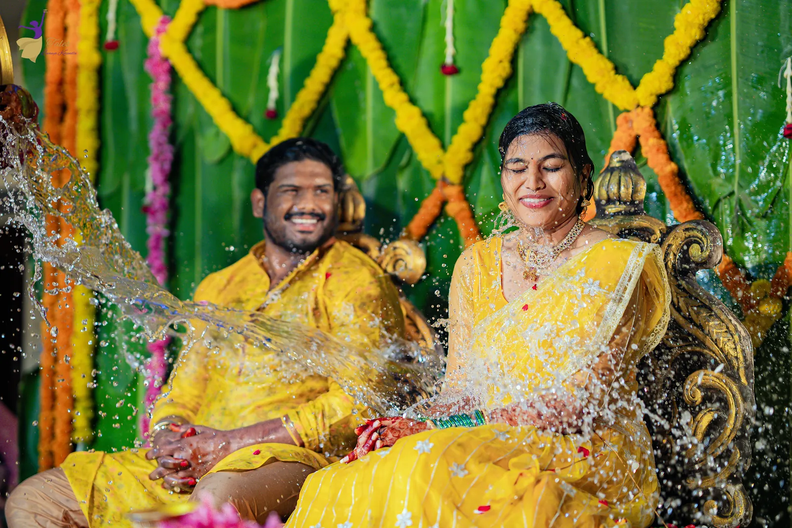 Water splashing over Ravinder and Anuhya as they laugh together at their haldi