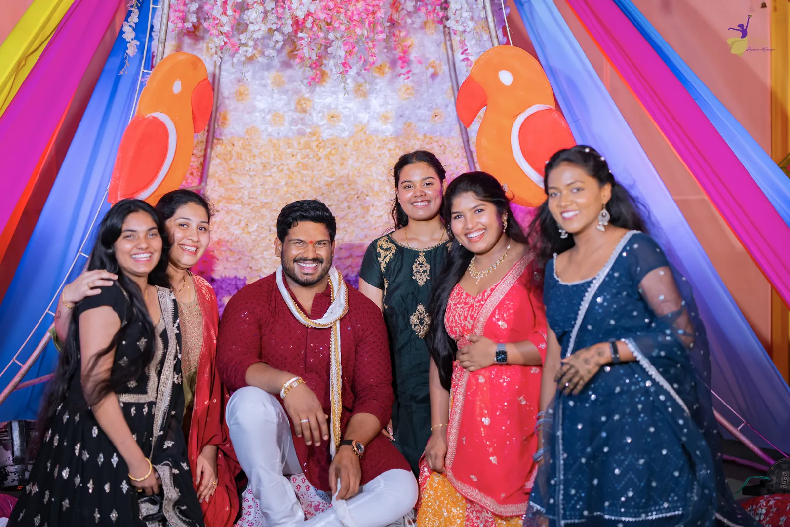 Ravinder with his cousins posing on the bright rainbow-draped mehendi stage