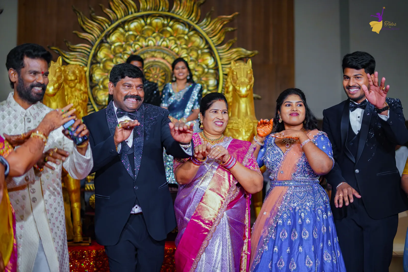 Ravinder and Anuhya dancing with their cousins in front of a golden sun backdrop