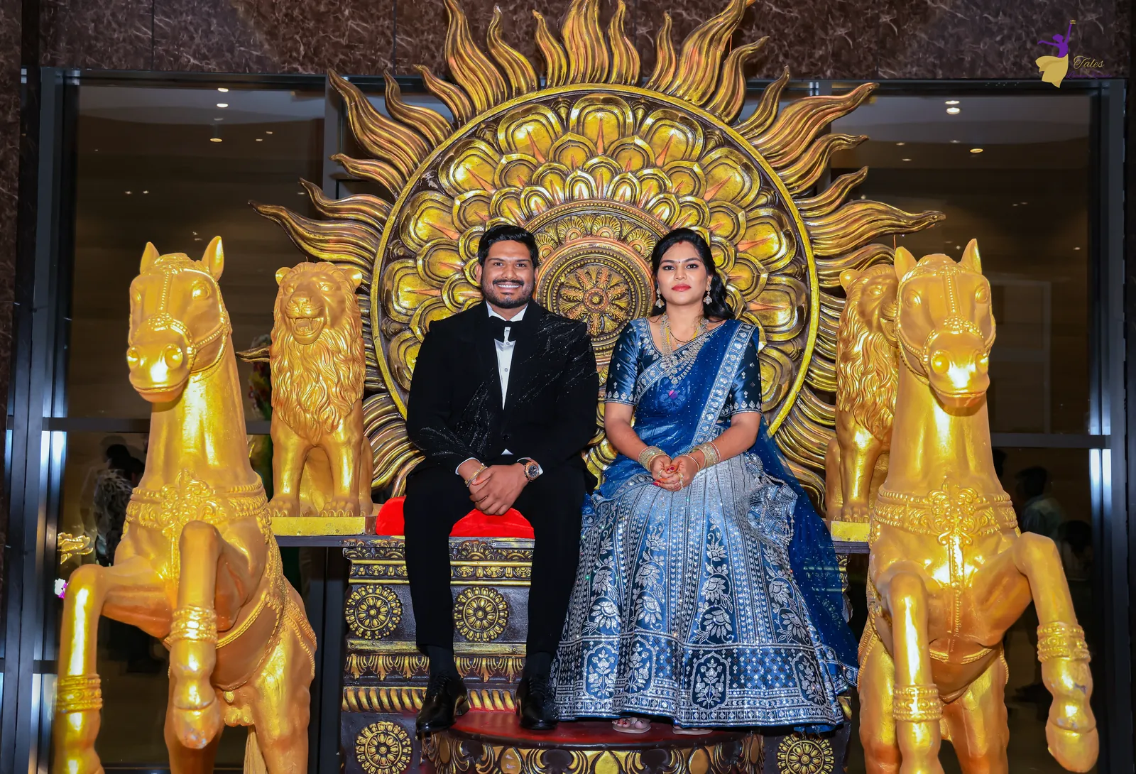 Ravinder and Anuhya seated on a golden sun throne flanked by golden horse sculptures