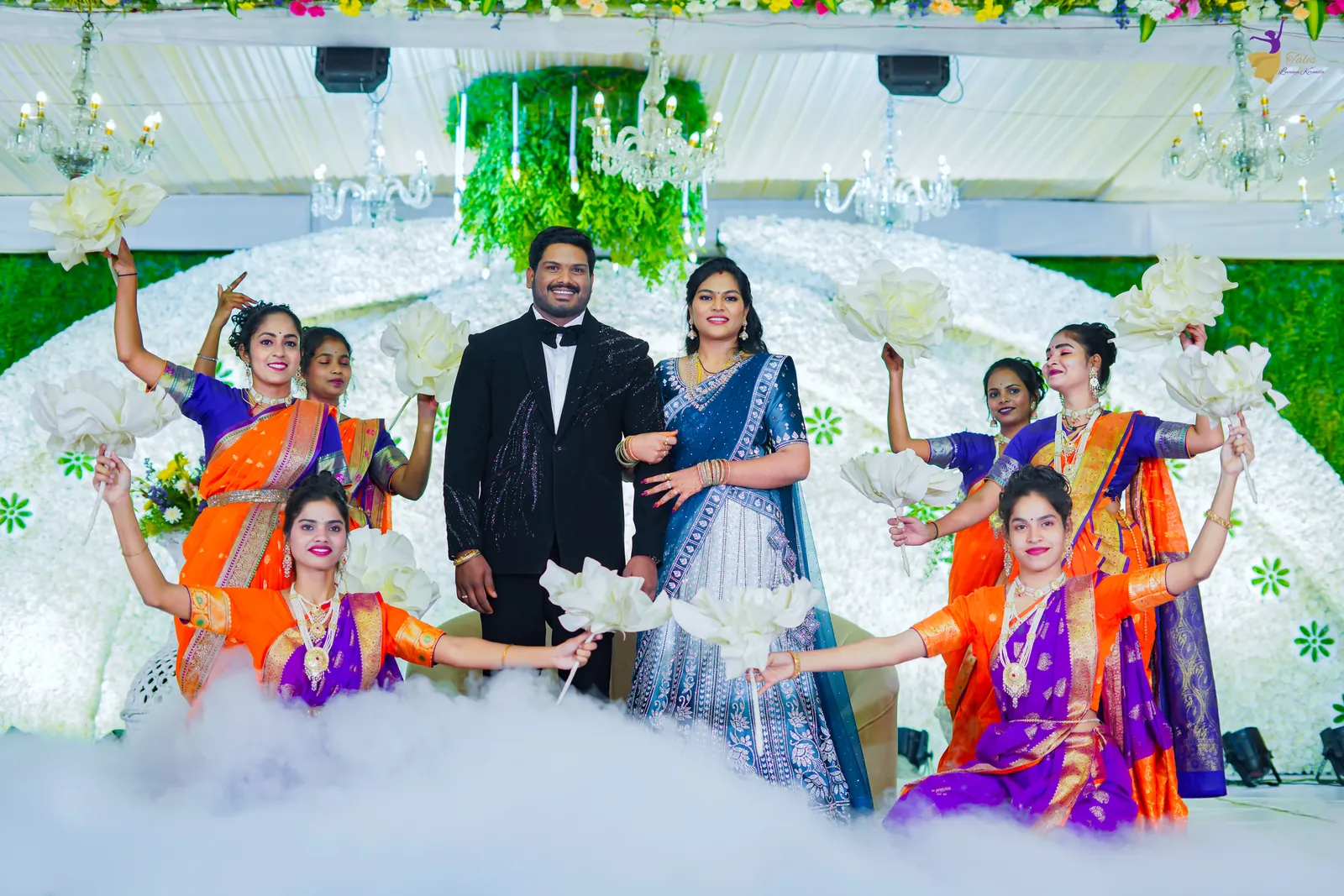 Wide shot of the couple’s fog-filled stage entry framed by dancers holding white flowers
