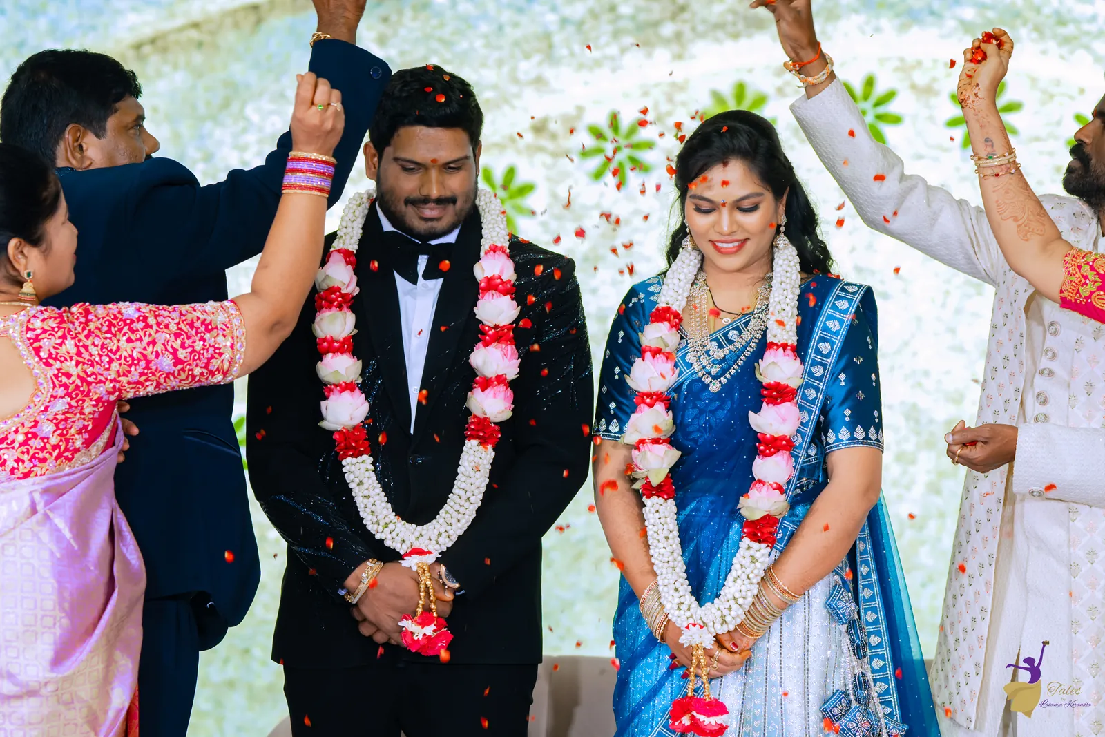 Ravinder in a black tuxedo and Anuhya in blue wearing flower garlands at their reception