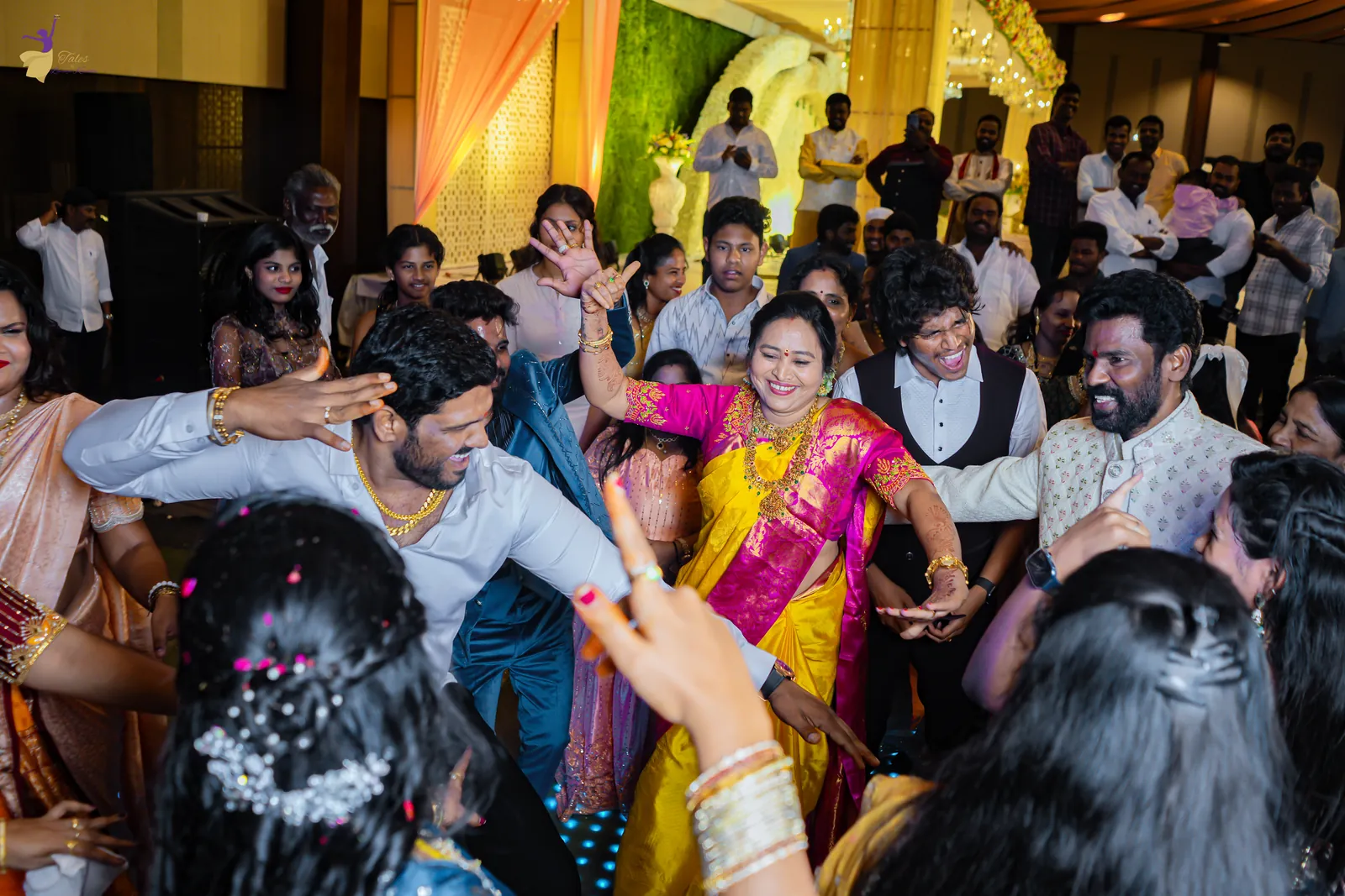 Wide shot of the crowded dance floor with the couple and cousins dancing together