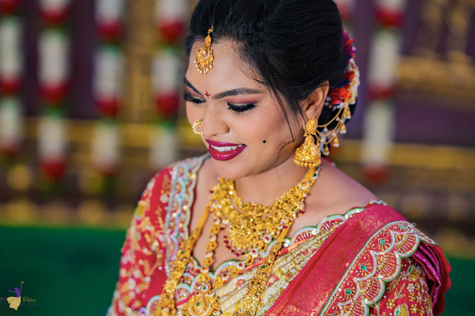 Close bridal portrait of Anuhya smiling in gold jewellery and a red silk saree