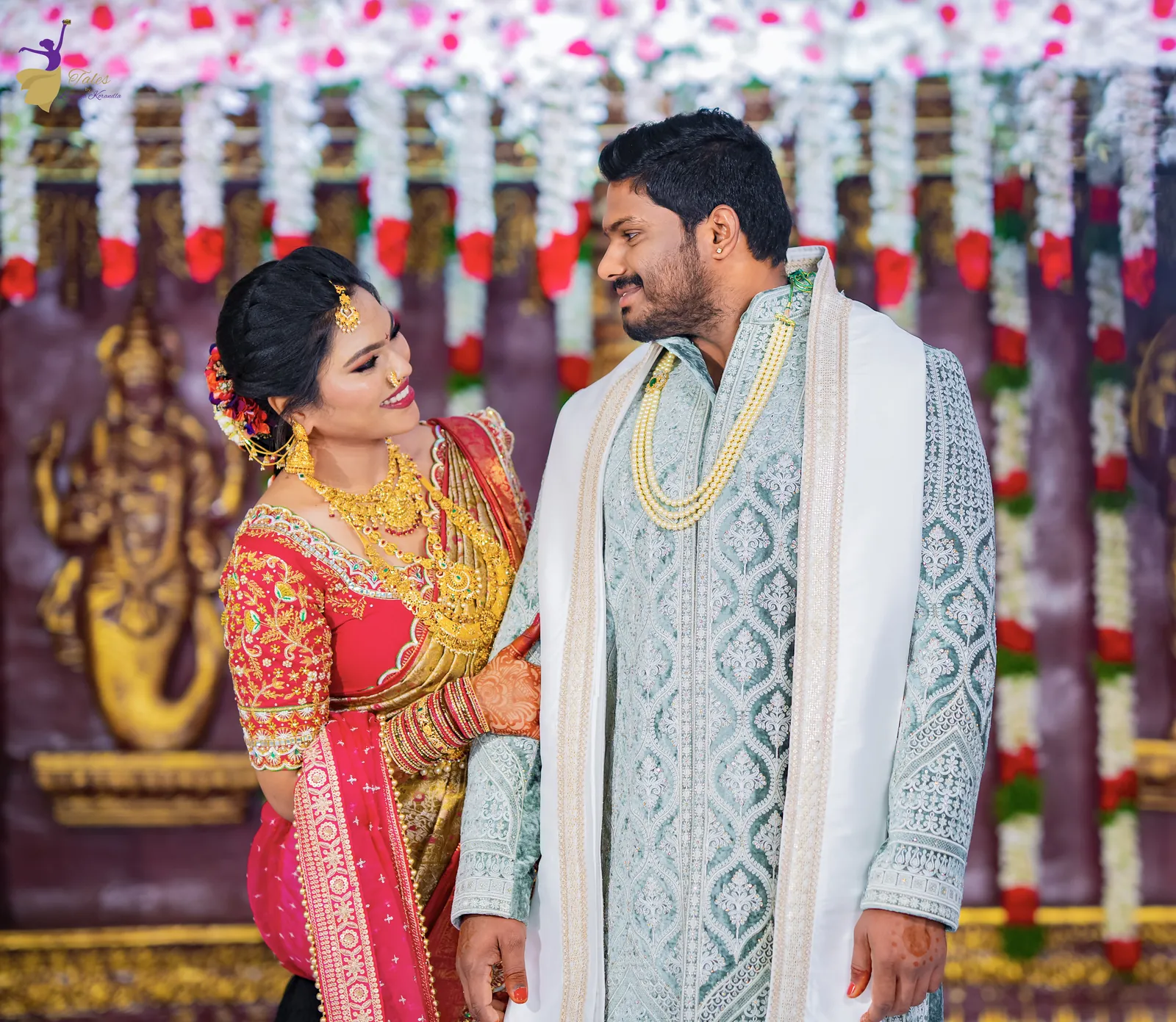 Anuhya in a red and gold silk saree gazing up at Ravinder in a pale blue sherwani