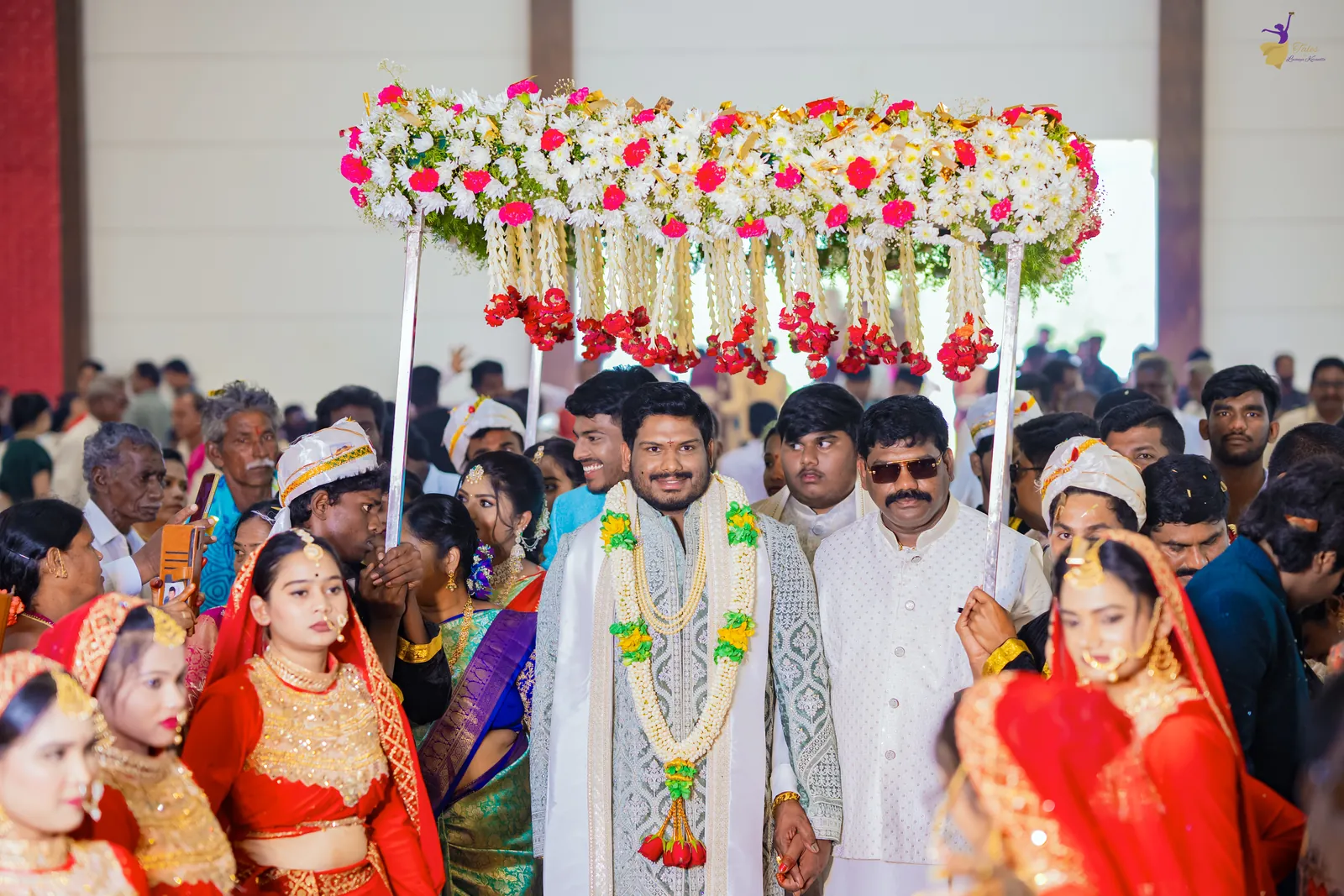 Groom Ravinder’s wedding entry under a flower canopy, surrounded by a cheering crowd