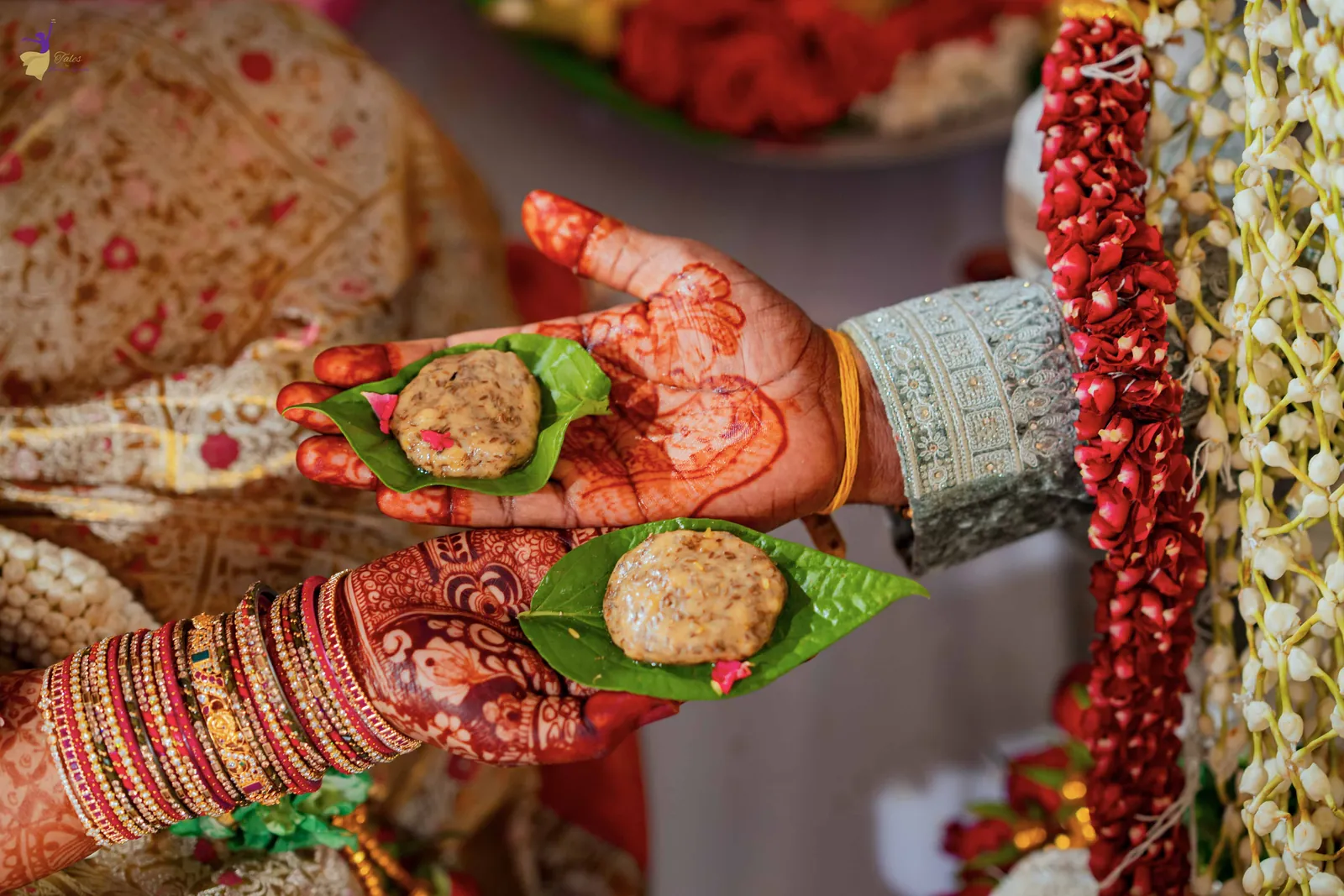 Close-up of mehendi hands holding jeelakarra bellam on betel leaves, Telugu wedding ritual