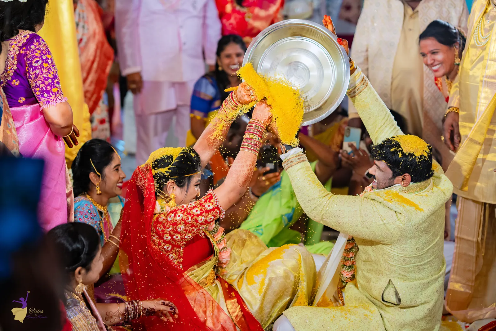 Ravinder pouring talambralu from a silver plate over Anuhya during the wedding rituals