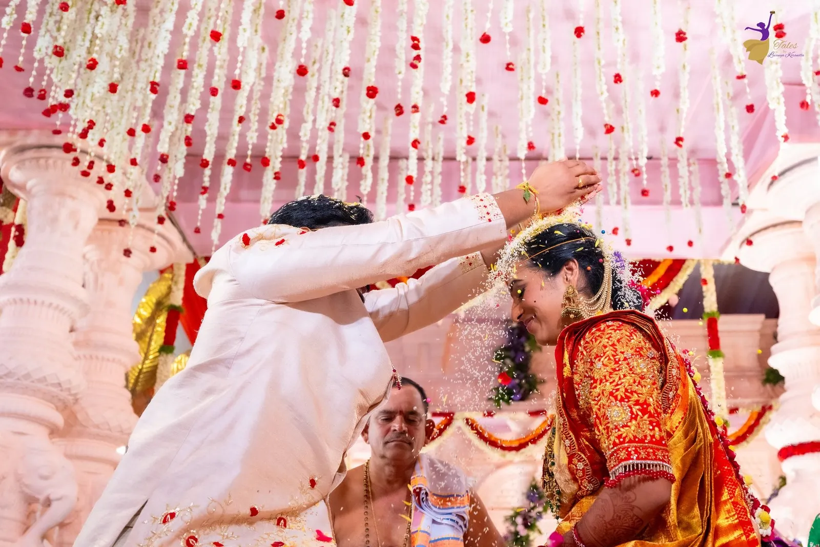 Manoj pouring sacred rice over Priya under floral garlands