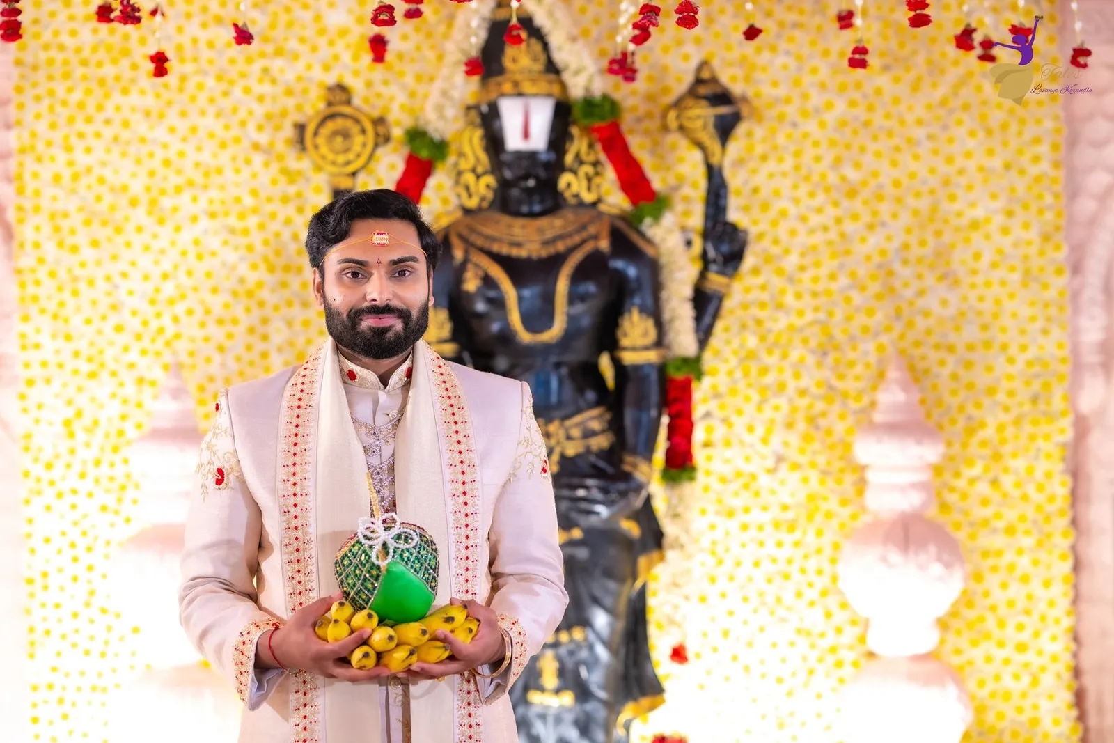 Manoj holding a ceremonial coconut before a golden deity backdrop