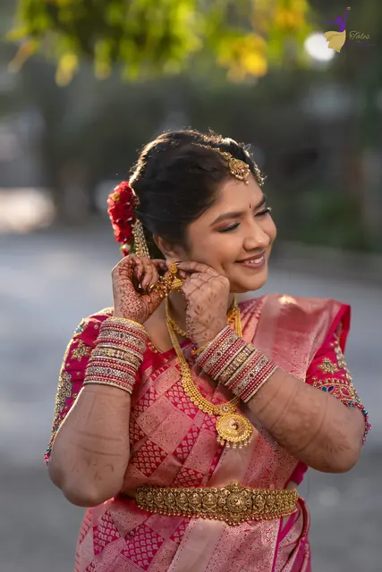 Priyanka adjusting her earring in warm early-morning backlight, bridal portrait