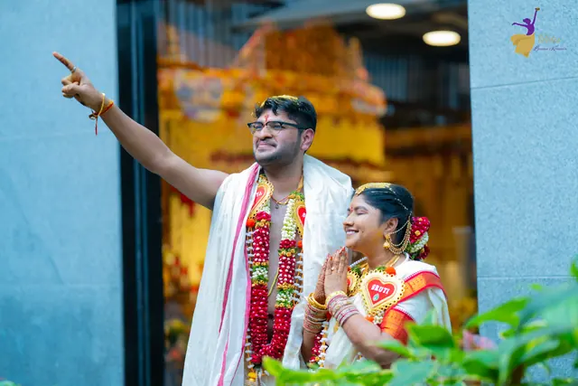 Aditya pointing to the sky as Priyanka smiles beside him, wedding portrait