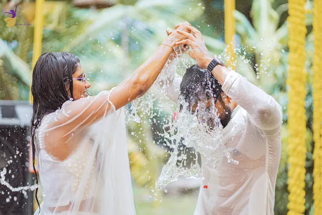 Water splashing over the couple as they play at their haldi celebration