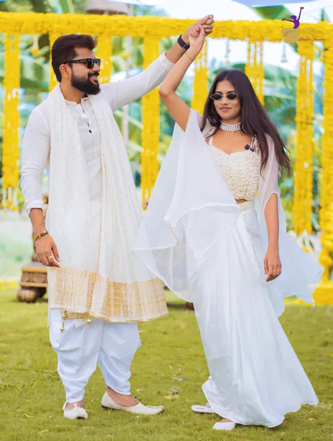 Couple in white twirling on the lawn under marigold strings at their haldi