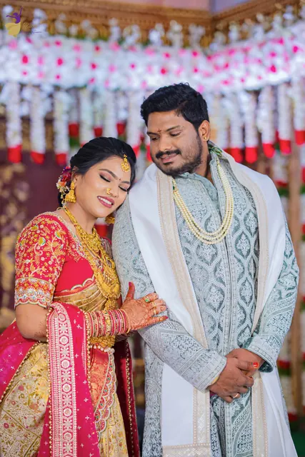 Anuhya smiling as she leans on Ravinder’s shoulder against a floral wedding backdrop