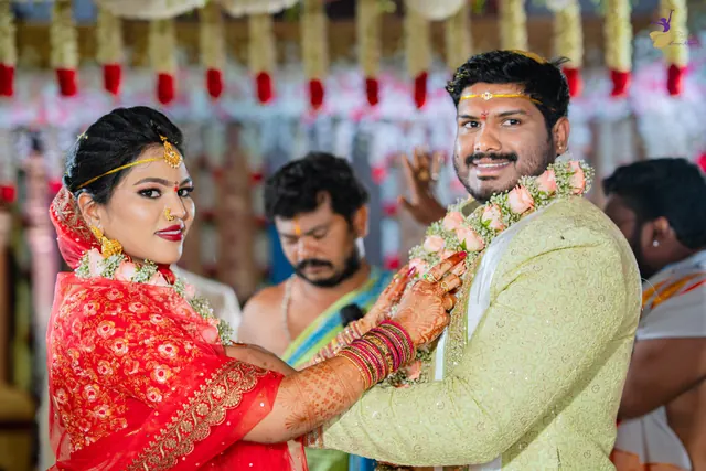 Anuhya smiling as she garlands Ravinder during the Telugu wedding ceremony