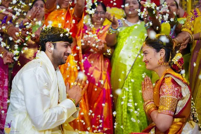 Bride and groom facing each other before yellow and red floral decor