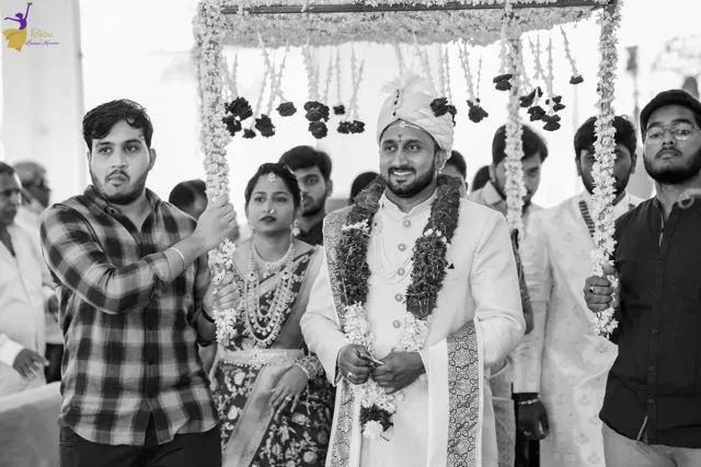 Black-and-white candid of groom walking through guests