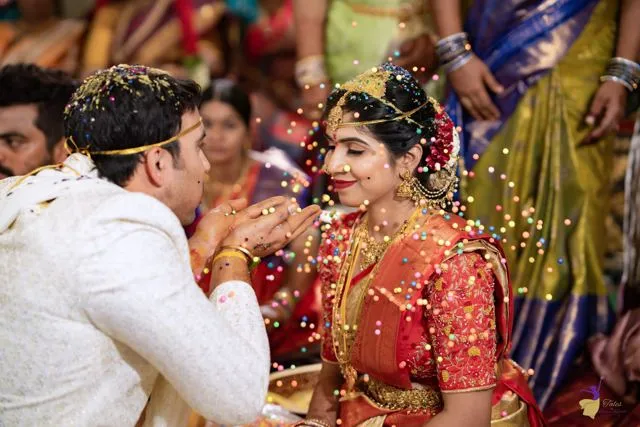 Smiling couple showered with yellow rice during Talambralu ceremony