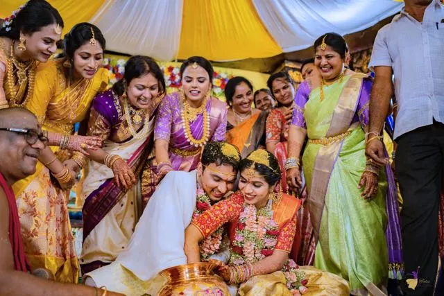Groom seated surrounded by family in yellow and green sarees