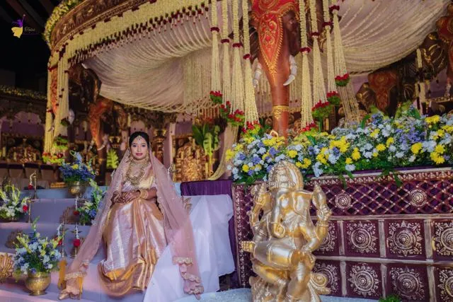 Bride on a stage with heavy floral arrangements, Hyderabad wedding