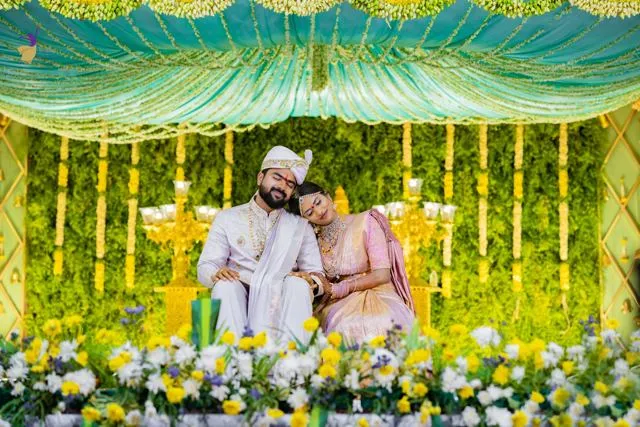 Couple seated on a ceremonial chair against yellow flowers