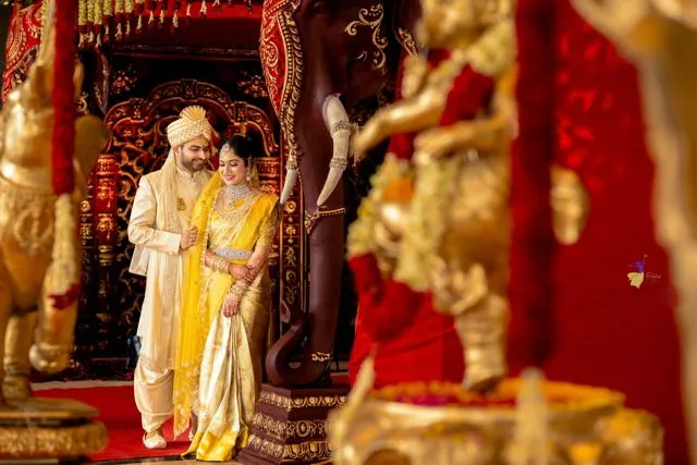 Couple in a grand hall with red drapery and golden idols