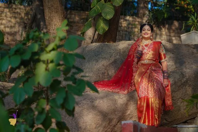 Bride in red saree on outdoor rocks among trees, Hyderabad wedding