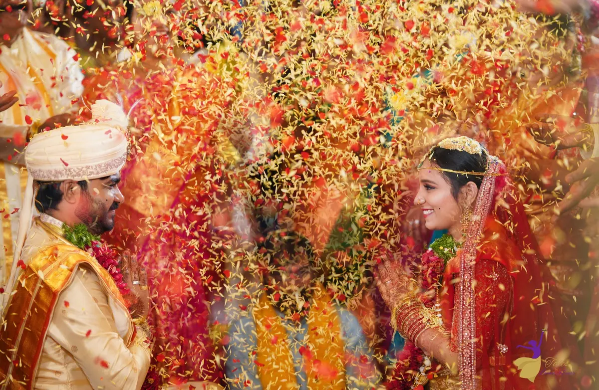 Couple showered with red and yellow flower petals during Talambralu, Telugu wedding